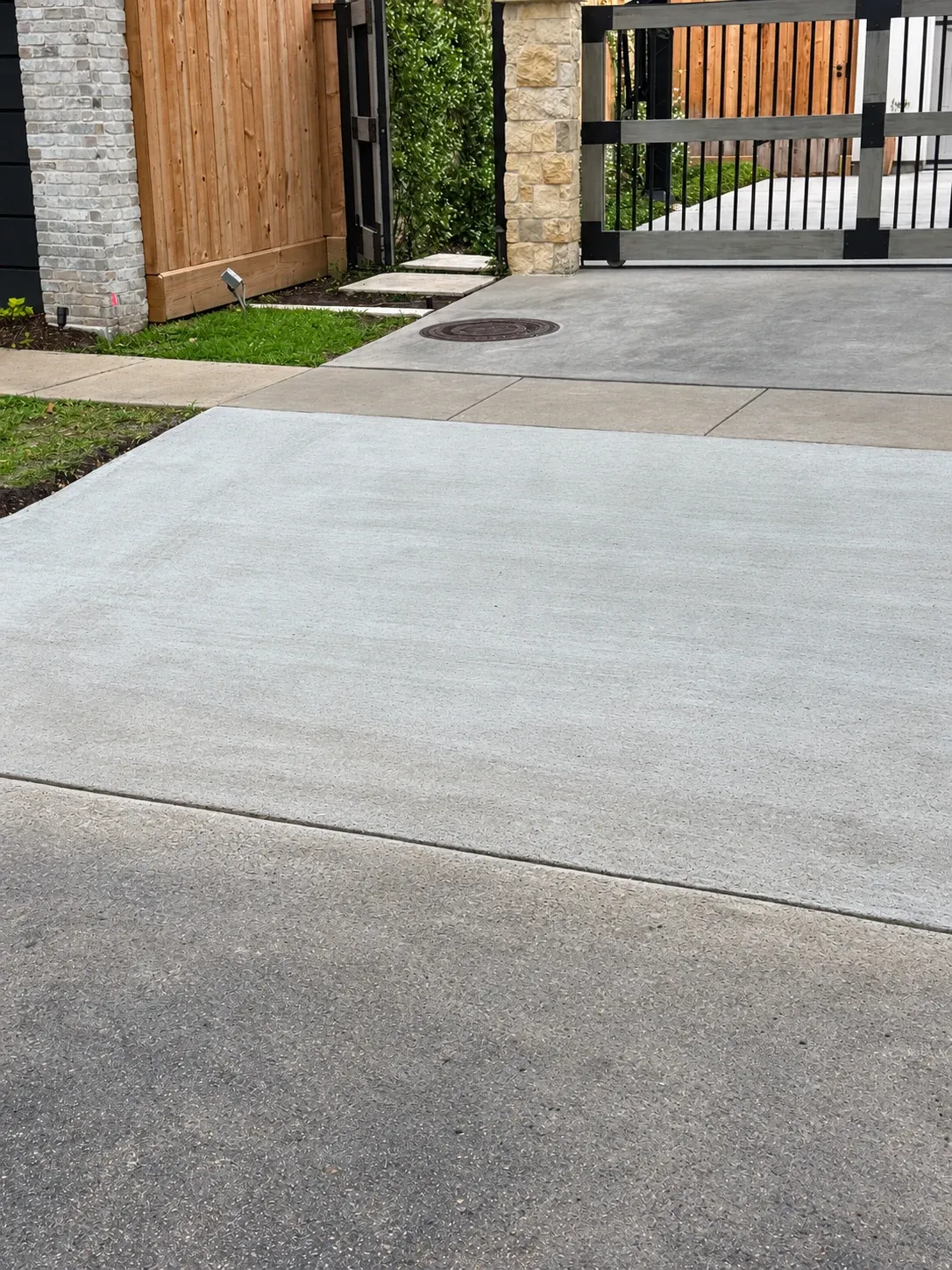 A finished concrete driveway running up to a gate.