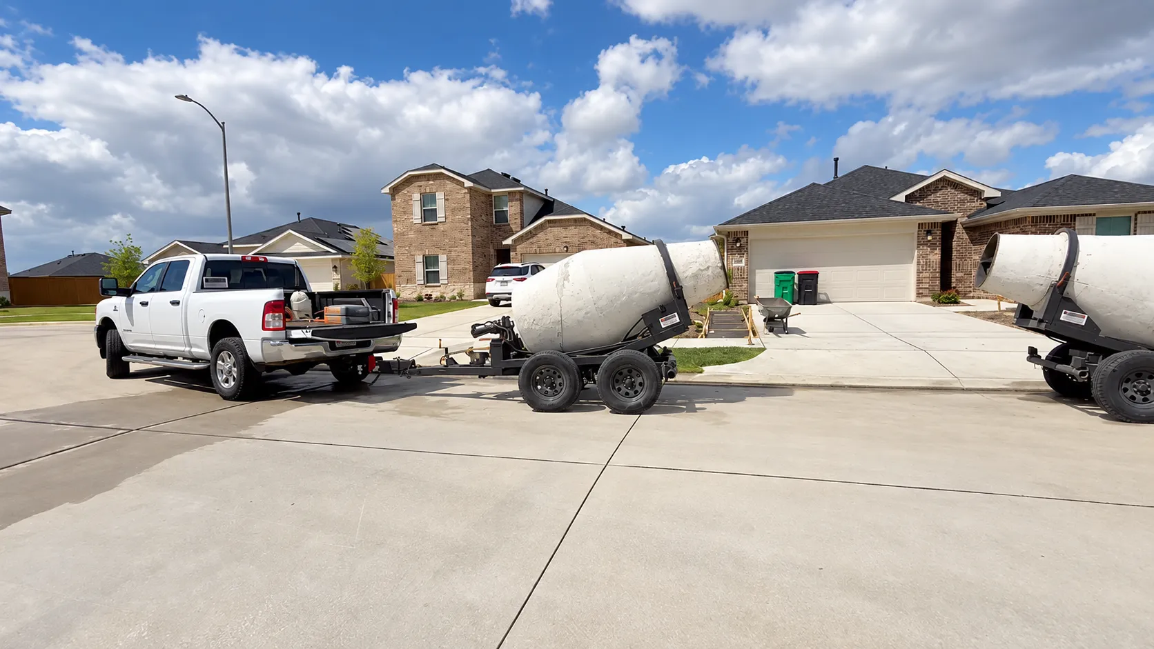 A white pickup with towable mixers on a residential driveway.