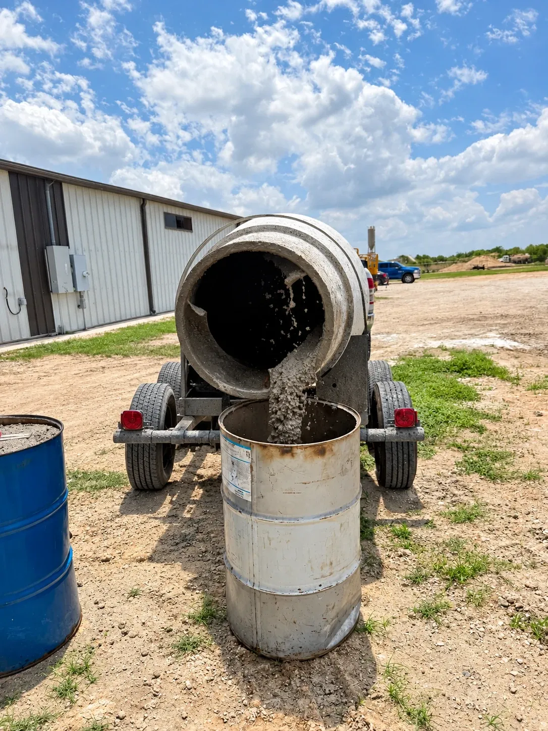 A towable mixer discharging into a steel drum at the yard.